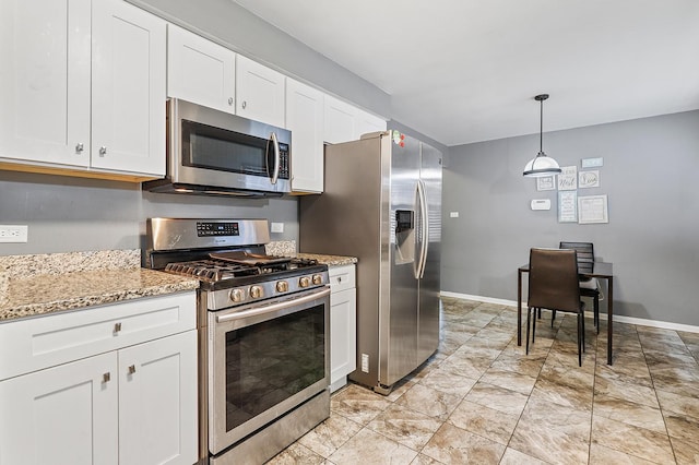 kitchen featuring stainless steel appliances, white cabinets, light stone counters, and decorative light fixtures