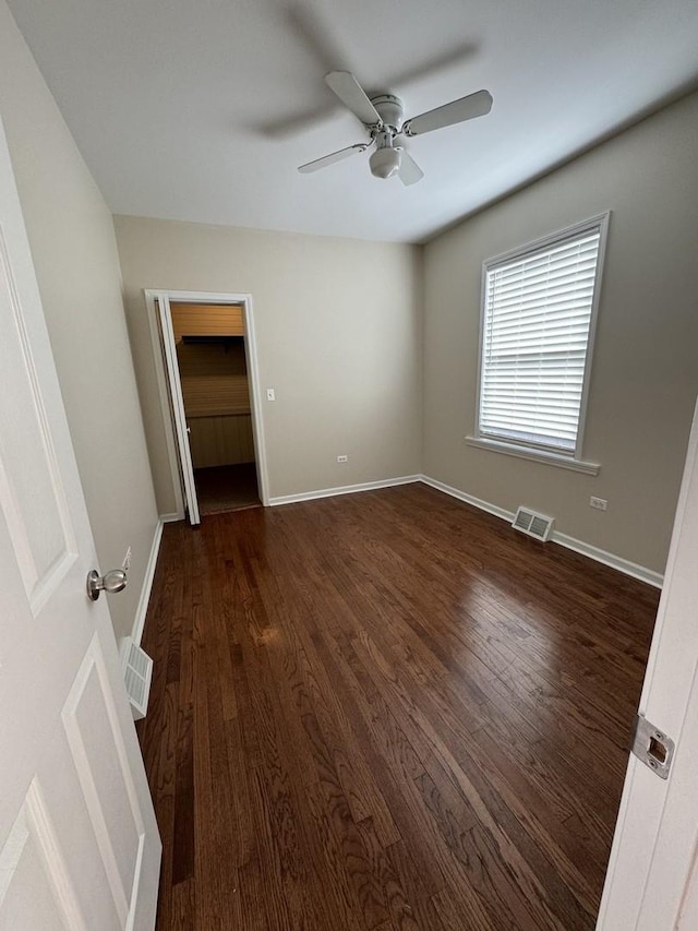 unfurnished bedroom with dark wood-style floors, visible vents, and baseboards