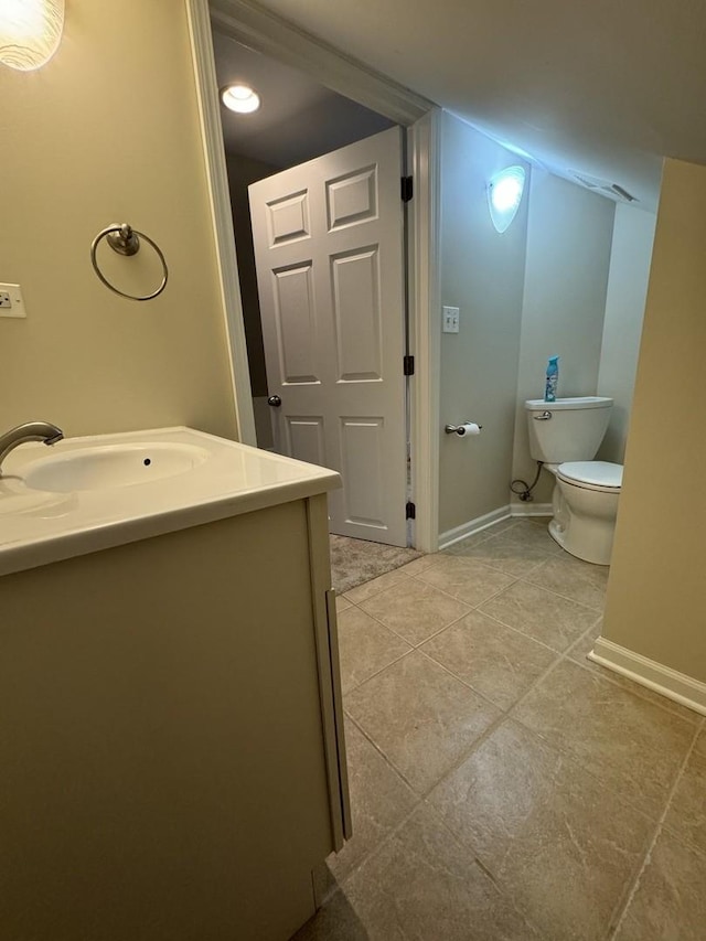 bathroom with tile patterned flooring, baseboards, vanity, and toilet