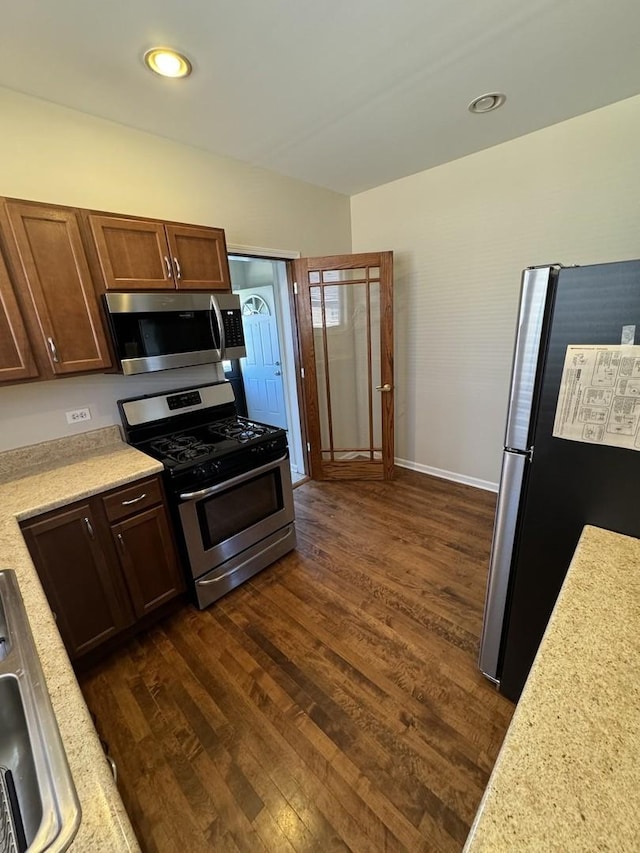 kitchen featuring appliances with stainless steel finishes, light countertops, a sink, and dark wood-style floors