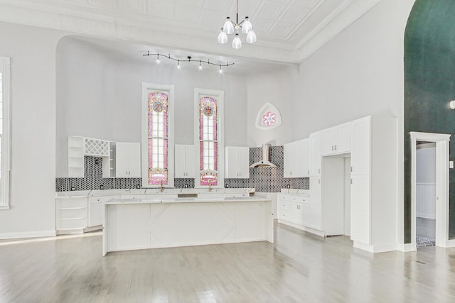 kitchen featuring pendant lighting, light hardwood / wood-style floors, a kitchen island, and ornamental molding