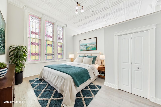 bedroom with light hardwood / wood-style flooring, a closet, and ornamental molding