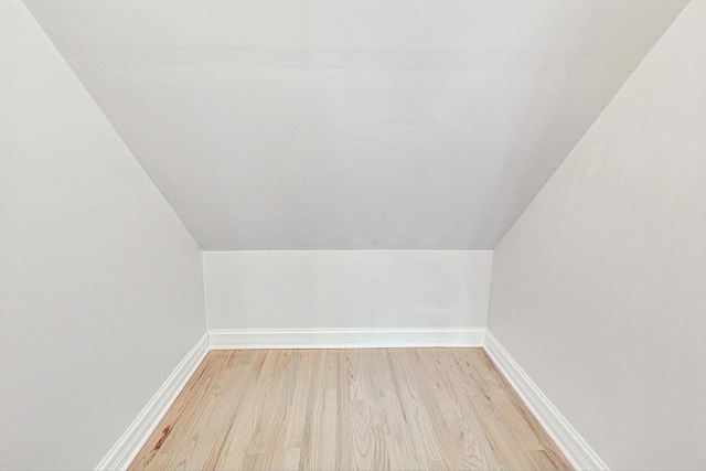 additional living space with light hardwood / wood-style floors and vaulted ceiling