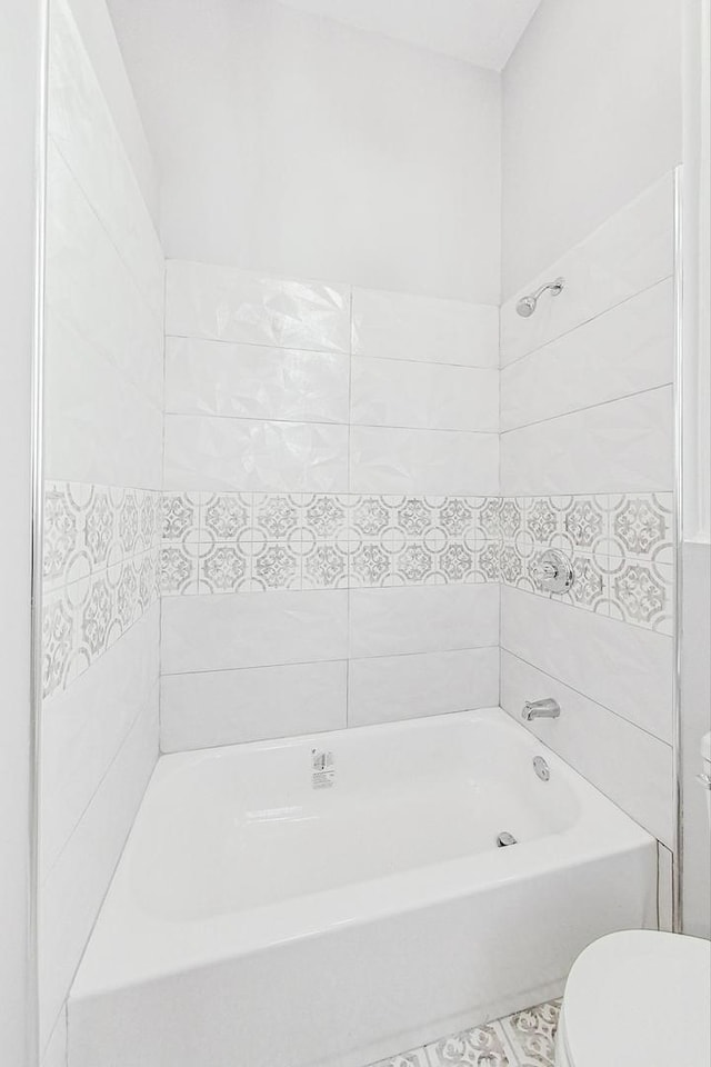 bathroom featuring tiled shower / bath combo and toilet