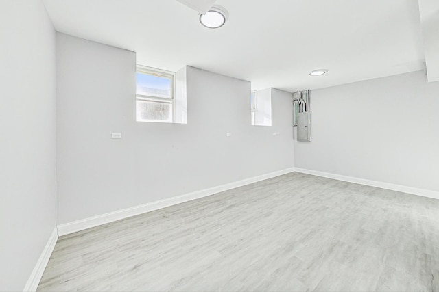 basement featuring electric panel and light hardwood / wood-style floors