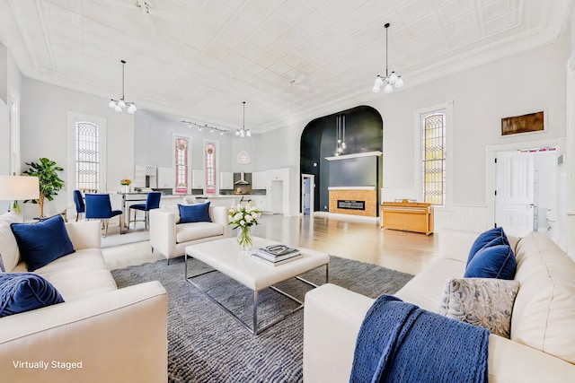 living room featuring hardwood / wood-style floors, plenty of natural light, ornamental molding, and a chandelier