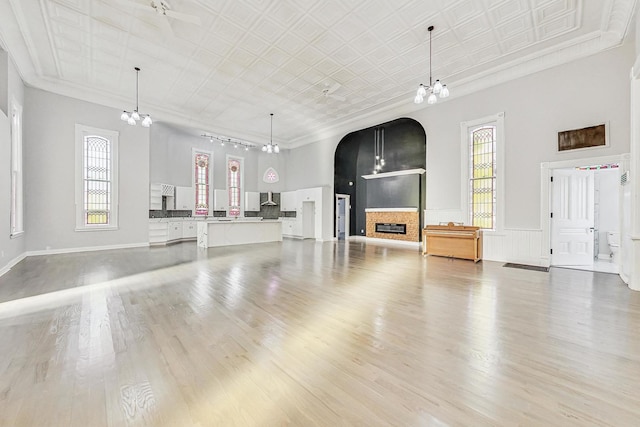 unfurnished living room featuring a high ceiling, light hardwood / wood-style floors, and plenty of natural light