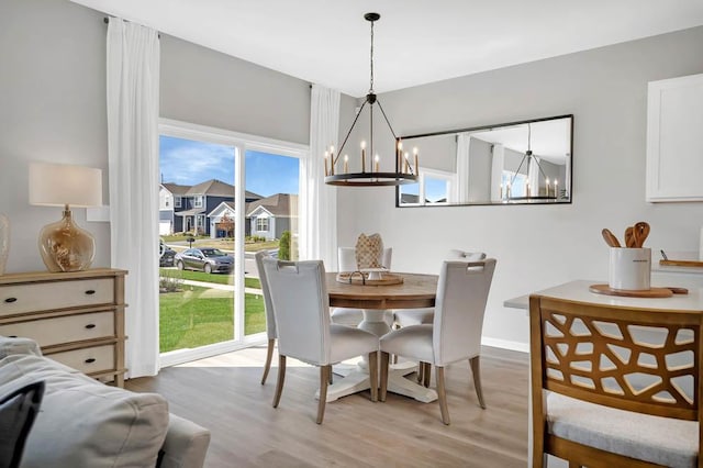 dining space with light hardwood / wood-style floors and an inviting chandelier