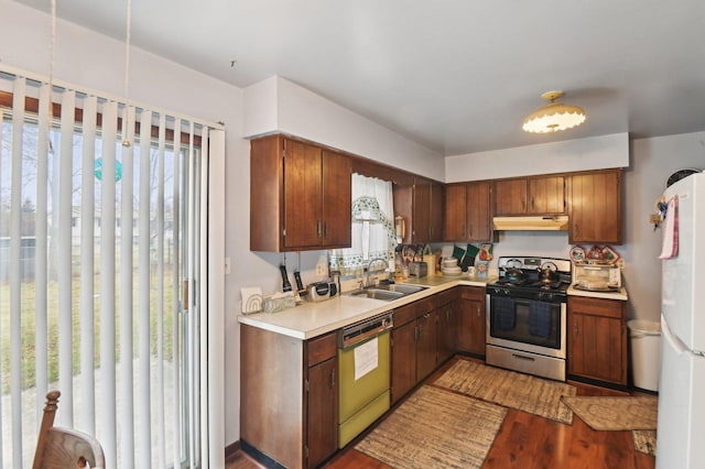 kitchen featuring dishwasher, sink, stainless steel stove, hardwood / wood-style flooring, and white fridge