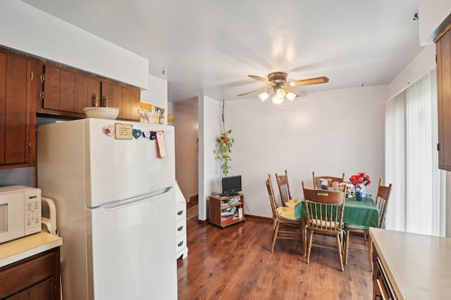 kitchen featuring ceiling fan, white appliances, and dark wood-type flooring