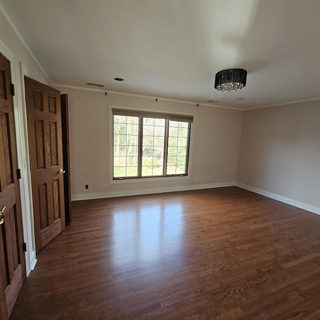 empty room featuring ornamental molding and dark wood-type flooring