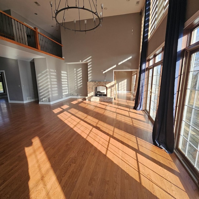 unfurnished living room featuring a fireplace, hardwood / wood-style floors, and a high ceiling