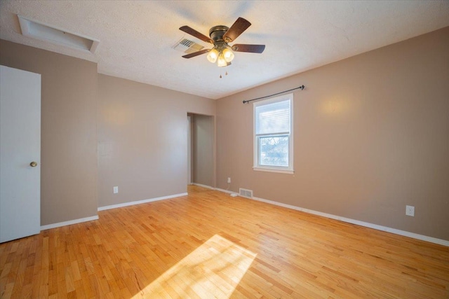 empty room featuring ceiling fan, light wood-type flooring, and a textured ceiling