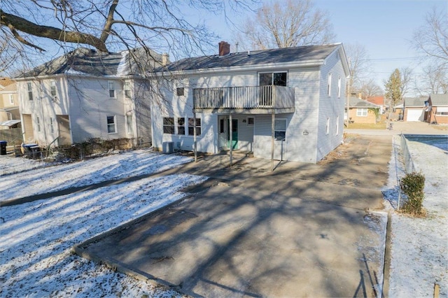 snow covered property featuring central AC unit and a balcony