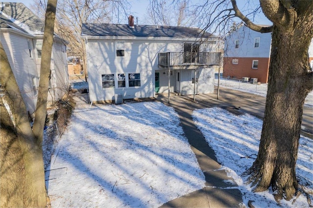 snow covered rear of property featuring a balcony