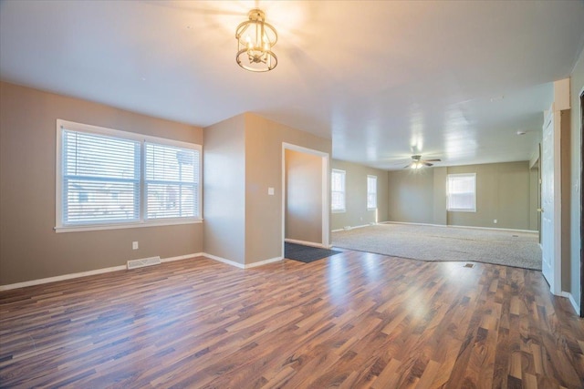 empty room with ceiling fan with notable chandelier and dark hardwood / wood-style flooring