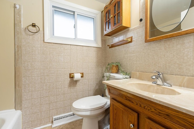 bathroom with vanity, a bathtub, toilet, and tile walls