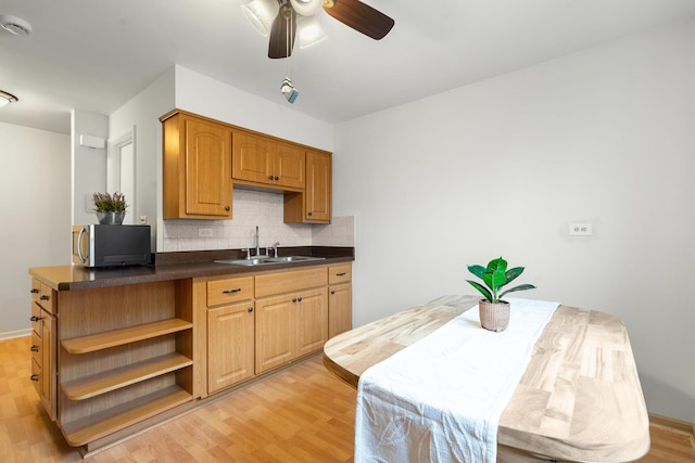 kitchen featuring decorative backsplash, light wood-type flooring, ceiling fan, and sink