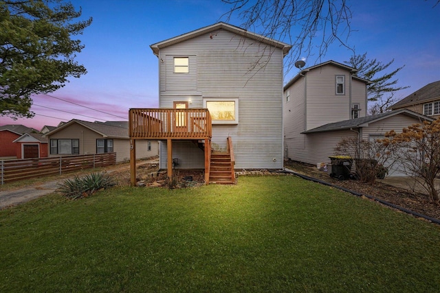 back house at dusk featuring a lawn and a wooden deck