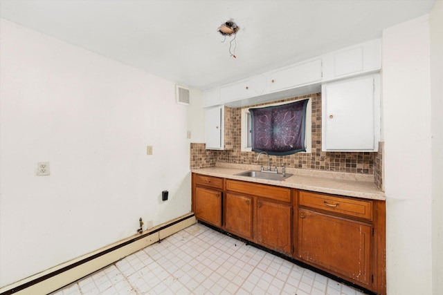 kitchen with backsplash, baseboard heating, and sink