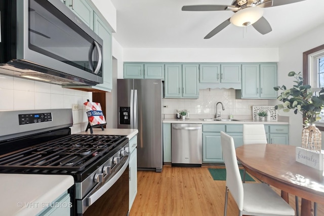 kitchen featuring ceiling fan, tasteful backsplash, sink, light wood-type flooring, and stainless steel appliances