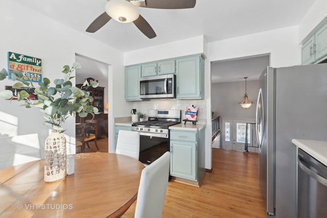 kitchen with pendant lighting, appliances with stainless steel finishes, decorative backsplash, light hardwood / wood-style floors, and ceiling fan