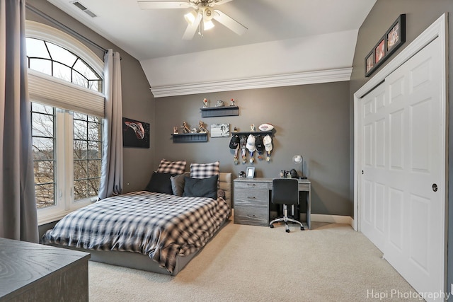 bedroom with vaulted ceiling, light colored carpet, ceiling fan, and a closet