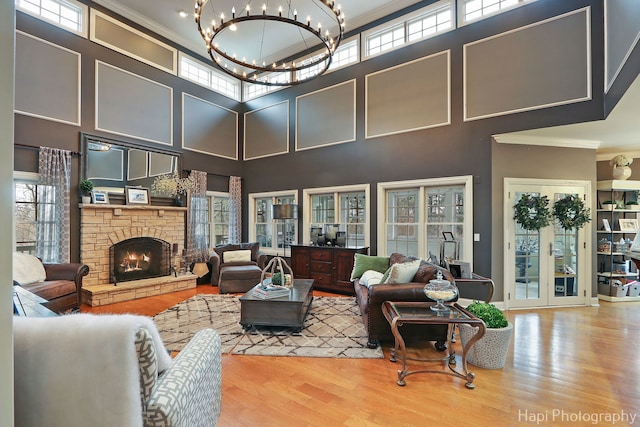 living room featuring hardwood / wood-style floors, crown molding, a stone fireplace, and plenty of natural light