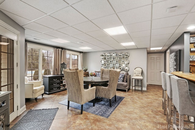 dining area with a paneled ceiling and tile patterned floors