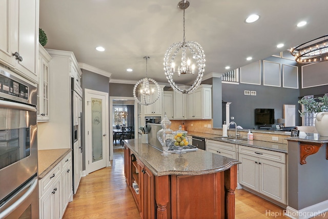 kitchen featuring sink, white cabinetry, decorative light fixtures, double oven, and a kitchen island