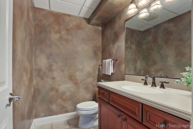 bathroom featuring vanity, toilet, tile patterned flooring, and a drop ceiling