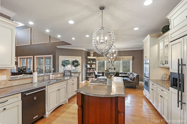 kitchen featuring sink, appliances with stainless steel finishes, an inviting chandelier, hanging light fixtures, and light hardwood / wood-style floors