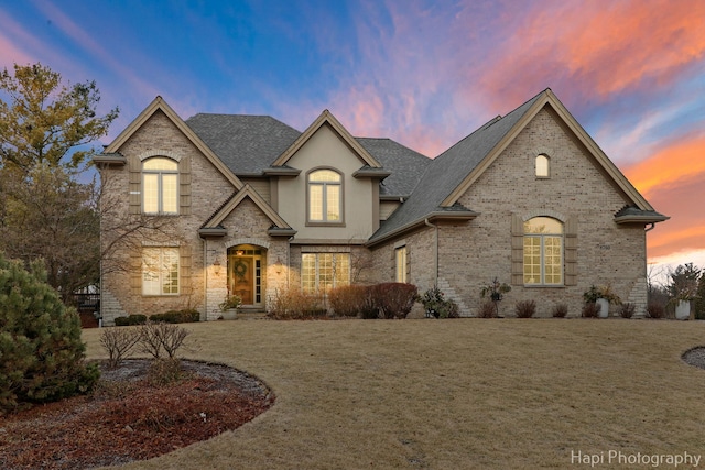 french country inspired facade featuring a lawn