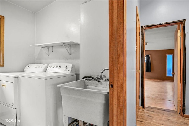 laundry area with light hardwood / wood-style floors, sink, and washing machine and clothes dryer