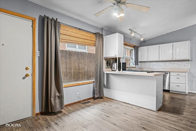 kitchen featuring white cabinets, light wood-type flooring, kitchen peninsula, and lofted ceiling