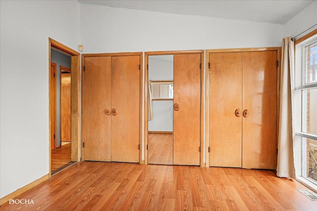 unfurnished bedroom with multiple closets and light hardwood / wood-style floors