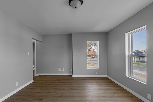 unfurnished room with a healthy amount of sunlight and dark wood-type flooring