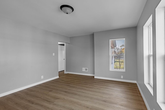 empty room with plenty of natural light and hardwood / wood-style flooring