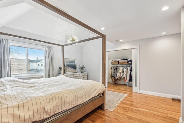 bedroom featuring a closet, a walk in closet, wood-type flooring, and a notable chandelier