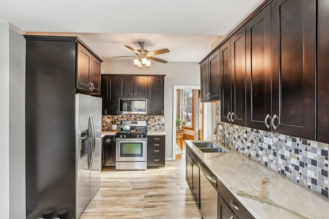 kitchen featuring light stone countertops, dark brown cabinetry, appliances with stainless steel finishes, decorative backsplash, and sink