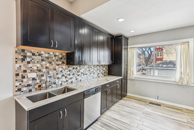 kitchen with decorative backsplash, sink, dishwasher, and light stone countertops