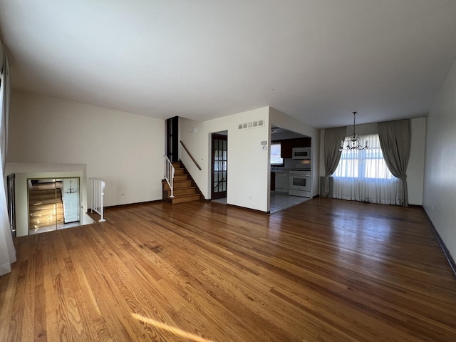 unfurnished living room featuring dark hardwood / wood-style flooring and an inviting chandelier