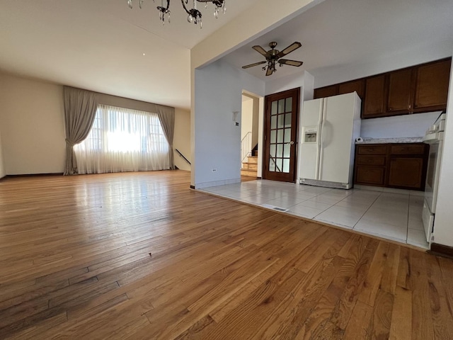 interior space featuring beamed ceiling, ceiling fan with notable chandelier, and light hardwood / wood-style floors