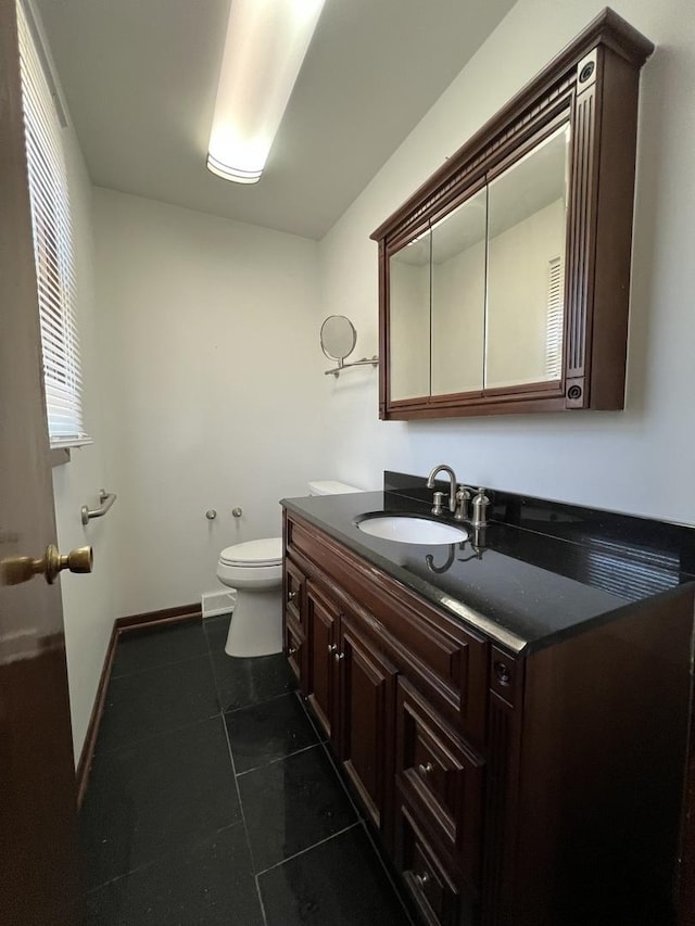 bathroom with toilet, vanity, and tile patterned floors