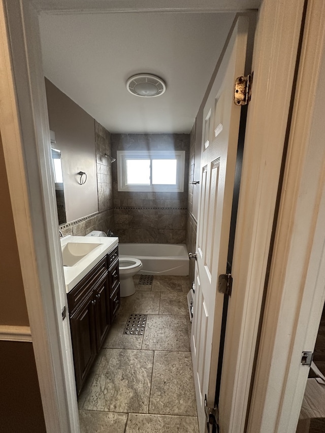 full bathroom with tiled shower / bath, vanity, and toilet