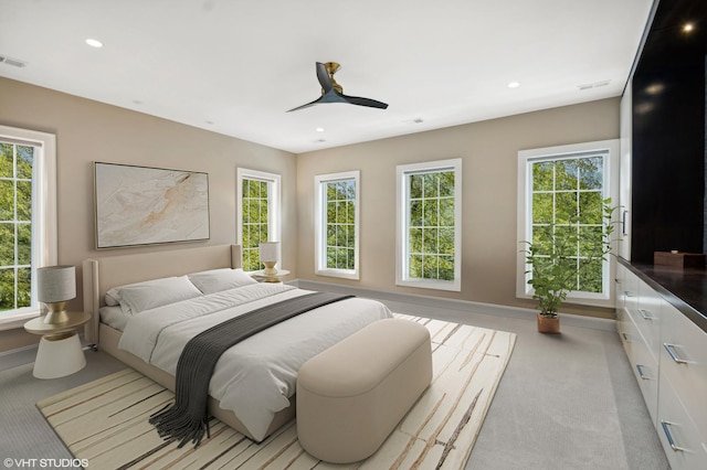 bedroom featuring light carpet, multiple windows, and ceiling fan