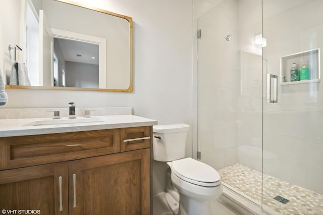 bathroom with a shower with door, vanity, and toilet