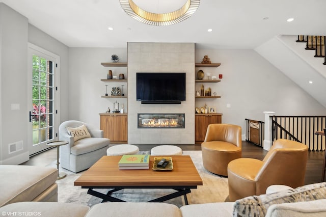 living room with a tile fireplace, lofted ceiling, and light wood-type flooring