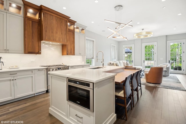 kitchen featuring pendant lighting, a kitchen island with sink, white cabinets, sink, and appliances with stainless steel finishes