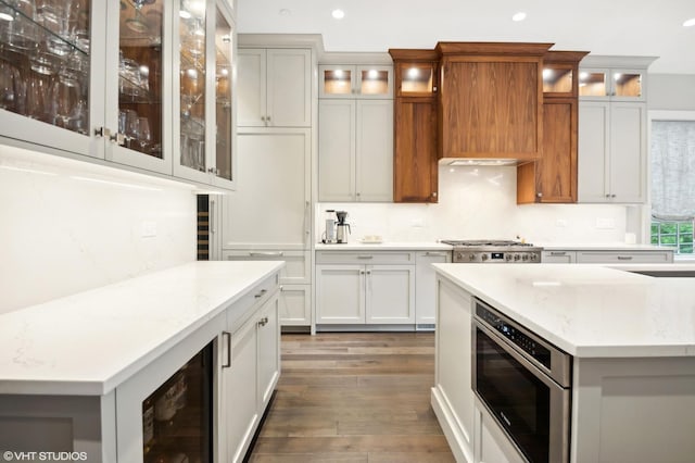 kitchen featuring white cabinets, light stone counters, dark wood-type flooring, and beverage cooler